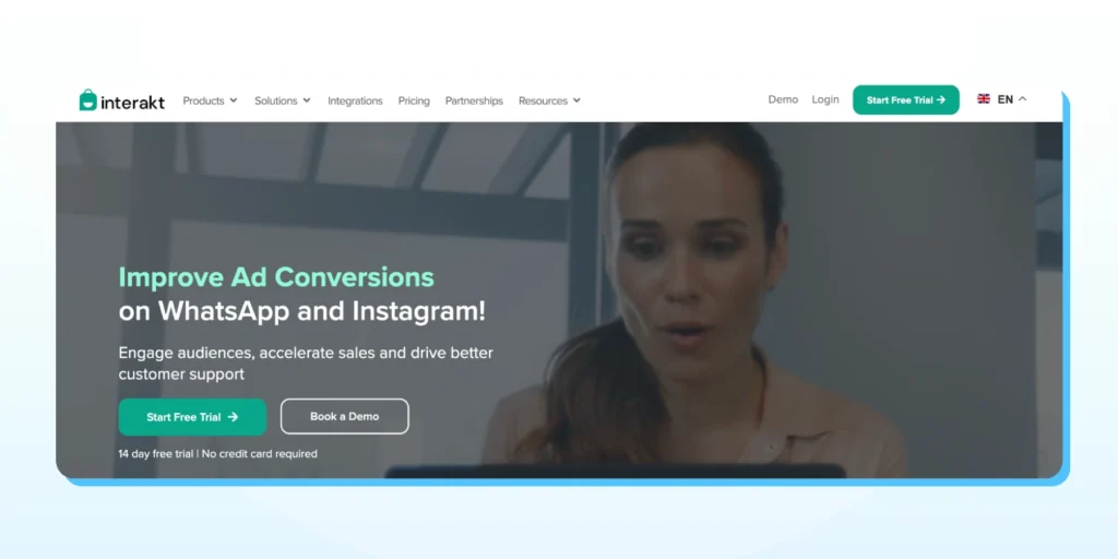 Interakt website banner featuring a woman looking at a laptop with text promoting WhatsApp and Instagram ad conversions.